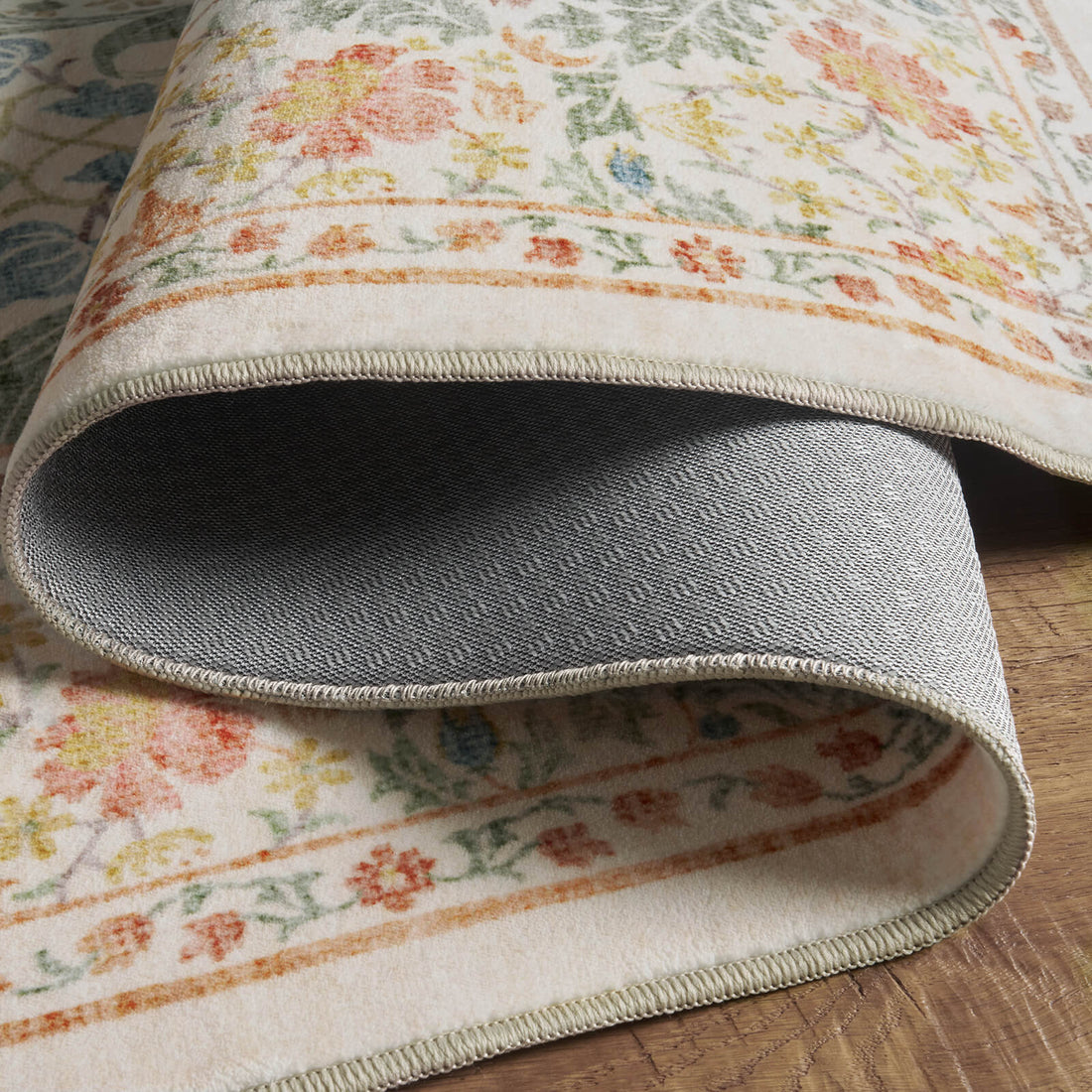 A close-up view of a washable vintage floral area rug showing the soft patterned surface and durable non-slip backing designed for comfort, stability, and everyday home use.