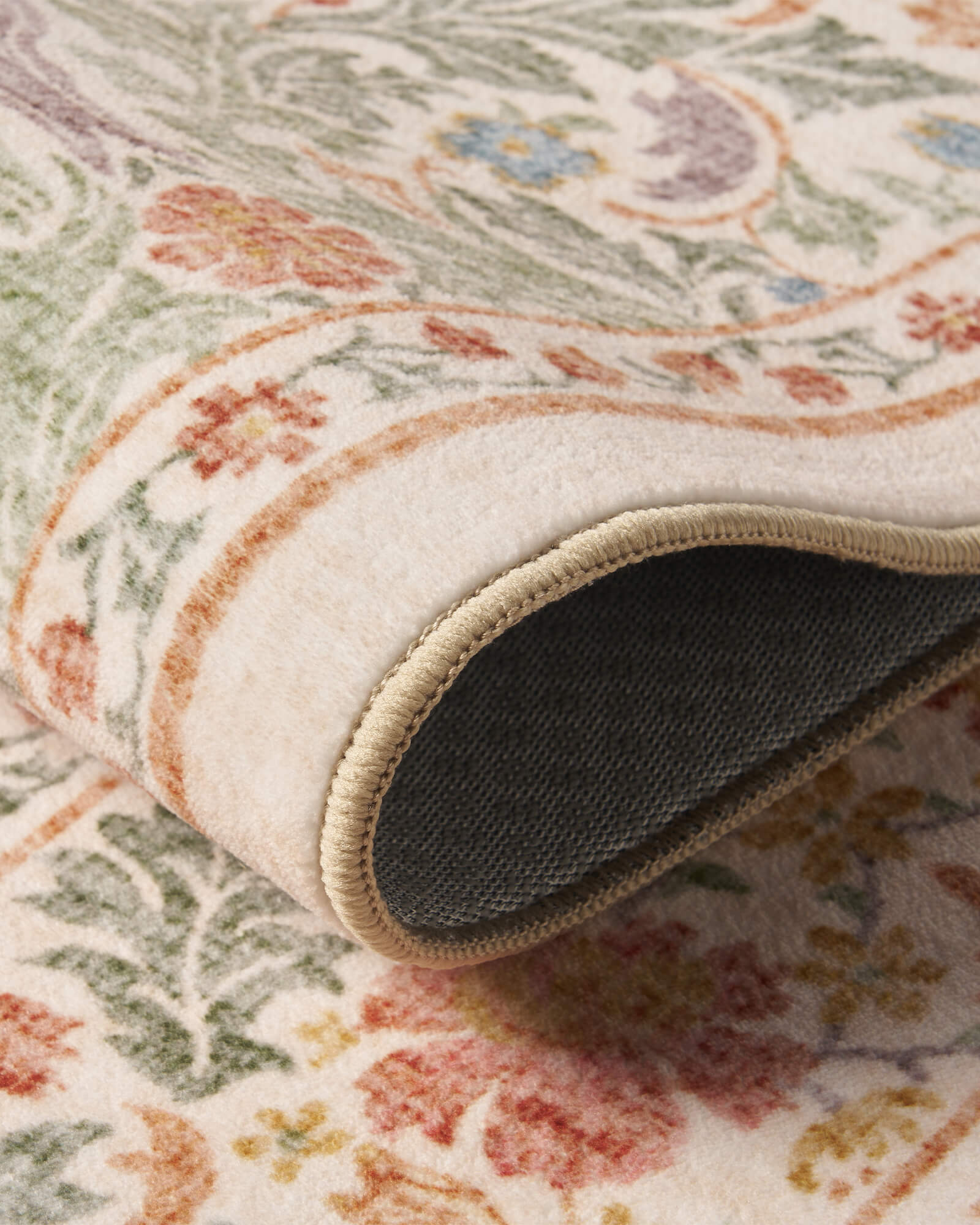 A close-up view of a washable vintage floral area rug featuring a soft botanical pattern, reinforced edges, and a durable non-slip backing for comfortable everyday use.
