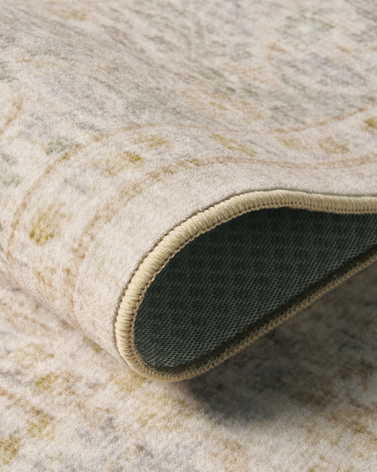 A close-up view of a washable vintage floral area rug showing its soft low-pile texture, flexible design, finished edges, and durable non-slip backing for comfortable everyday home use.