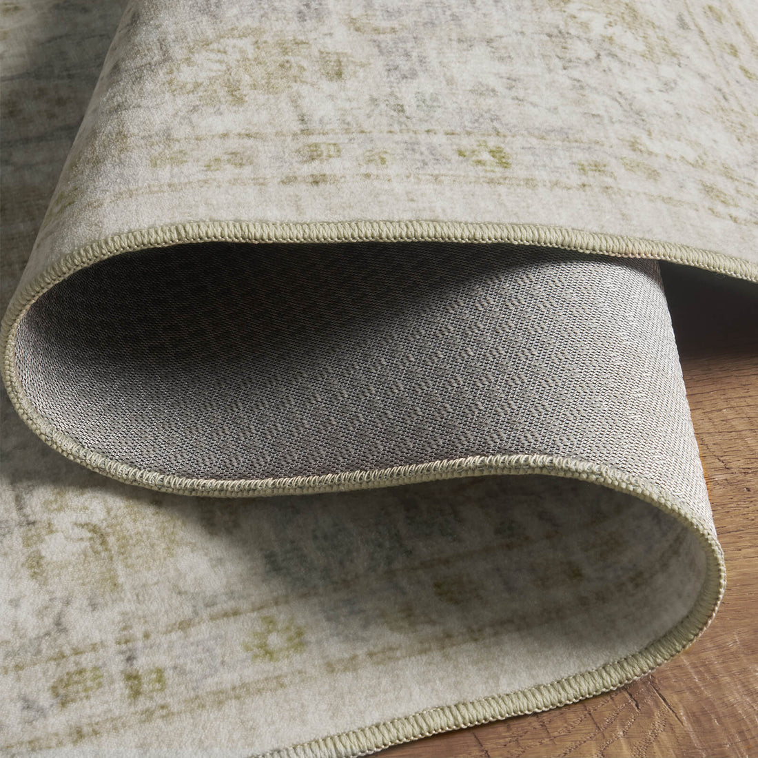 A close-up view of a washable vintage floral area rug showing its soft low-pile surface, flexible construction, and durable non-slip backing designed for comfortable and practical everyday home use.