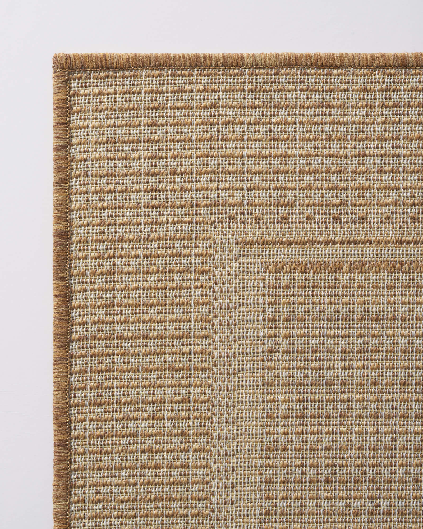 A woven indoor outdoor rug with a natural jute-look texture and reinforced edge adds durable, easy-care style to patios, porches, dining areas, and everyday living spaces.